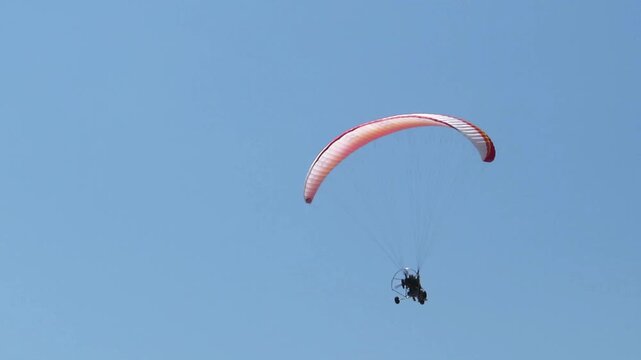 Motorized paraglider flying in sky