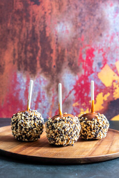 Caramel apples with peanuts and chocolate chips on a wood plate 