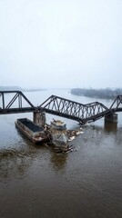 Fototapeta premium Collapsed railway bridge struck by a cargo barge in a wide river