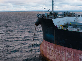 Aerial telephoto view of large cargo ship bow anchored at sea with heavy anchor chain dropped in Baltic Sea © Dmitri