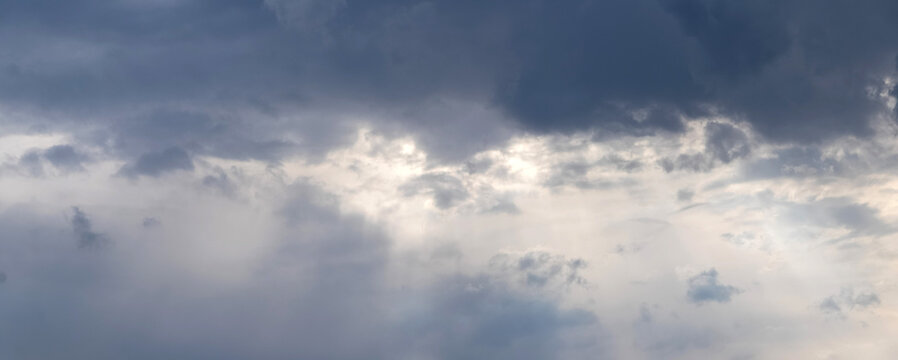 Panorama of a dramatic sky with dark blue storm clouds and light gaps on an overcast day before rain