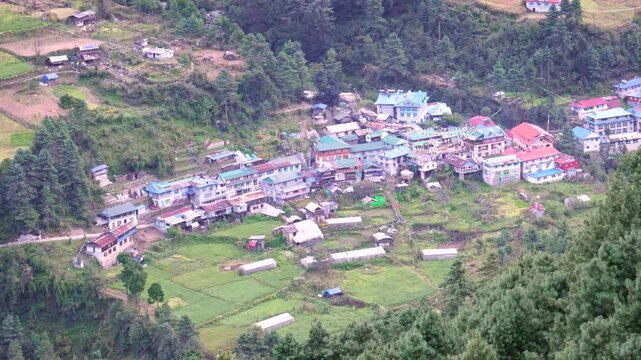 Stunning perspective of a traditional sherpa village surrounded by terraced fields and dense pine forests in the foothills of the magnificent himalayas, showcasing rural mountain life