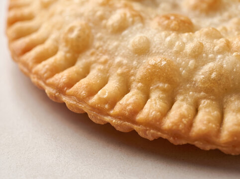 Macro close-up of crispy golden fried cheburek pastry crust with crimped edge