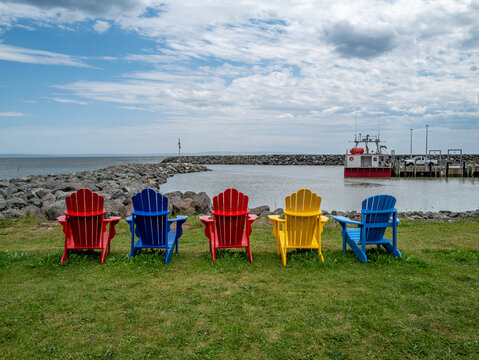 Colorful Adirondack chairs on a lawn overlooking the harbor in Alma, New Brunswick, Canada, July 2026.