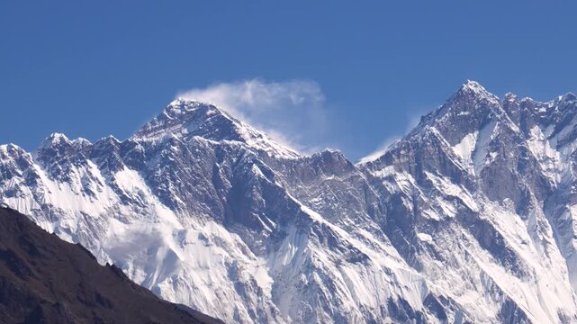Impressive view of majestic mount everest, the world's highest peak, with strong winds blowing snow plumes from its summit against a clear blue sky in the himalayas of nepal