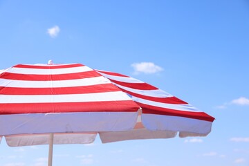Red striped beach umbrella under blue sky, closeup © New Africa
