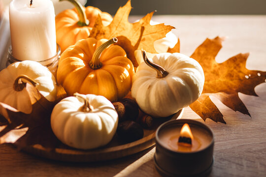 Aesthetics, seasonal atmospheric vibes. Thanksgiving dinner decor idea. Cozy home decoration on the windowsill with little pumpkins and candles. Aromatherapy for fall season.