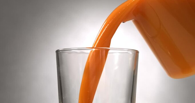 Fruit juice pouring into glass in slow motion