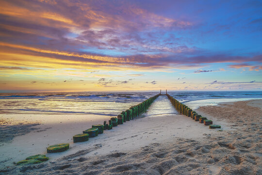 Sky ablaze with sunset hues, ocean whispers on sandy shores.
