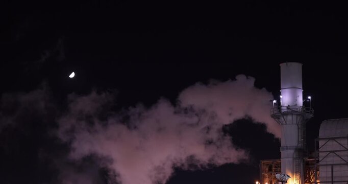 An oil refinery spews global warming causing carbon dioxide emissions at night. 