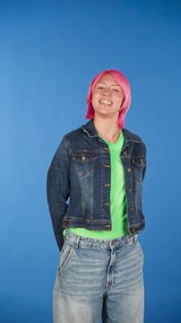 Young androgynous person with pink hair smiling at camera