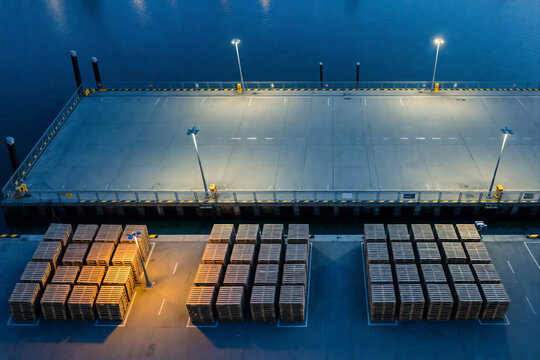 Port cargo pier with stacked wooden pallets at night