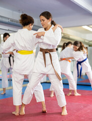 Women students athletes at Academy of martial Arts practice karate and fight opponents in pairs. Obtaining black belt, advanced training, highest dan of martial arts. Sport to max. . © JackF
