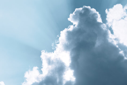 Dramatic cumulus cloud with bright sun rays in blue sky
