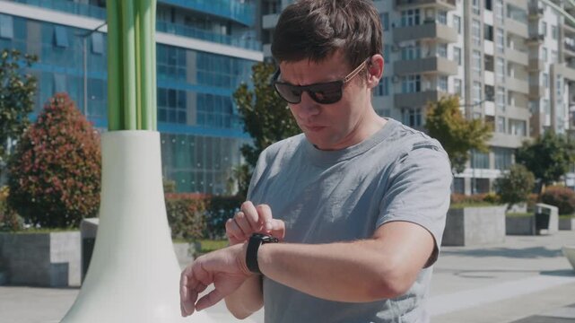 Man monitoring heart rate, activity and wellness on smartwatch fitness tracker outdoors.
