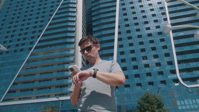 Man syncing smartwatch and smartphone fitness app to review workout results after training outdoors.
