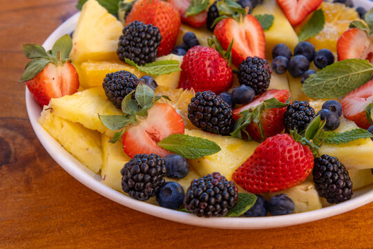 Fresh fruit and berry salad with mint on plate
