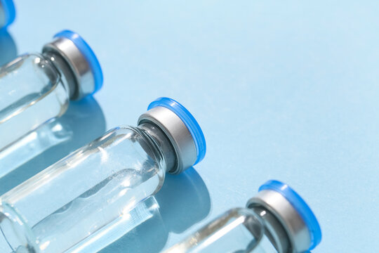Vaccination and immunization campaign, medical vials with clear liquid for injection on blue background for healthcare and pharmaceutical industry