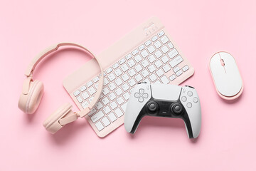 Gaming and remote work lifestyle, pink computer keyboard with wireless mouse, headphones and game controller on a pastel background for digital culture © Pixel-Shot