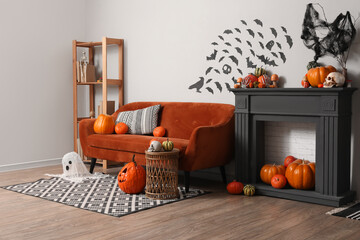 Fototapeta na wymiar Halloween home decor and festive interior, orange sofa with pumpkins and spooky decorations in a living room for autumn holiday celebration