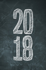 Number 2018 hand lettered in white chalk on a plain blackboard © janvaneyck
