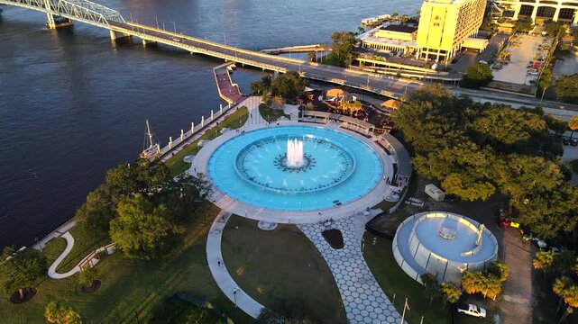 Moving aerial view reveals fountain plaza and calm river around Friendship Fountain in Florida.