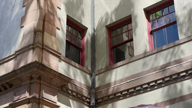 赤い窓枠と幾何学模様の装飾が美しいハワイの歴史的な建物と壁に映る木の影