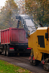 Road works, asphalt milling machine loading old pavement into dump truck. Urban infrastructure, modernization, asphalt recycling  © Alena Malinouskaya