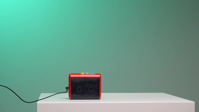Man's hands operating a vintage portable cassette player next to black headphones, highlighting a sense of nostalgia, retro audio technology, and listening to music from past decades