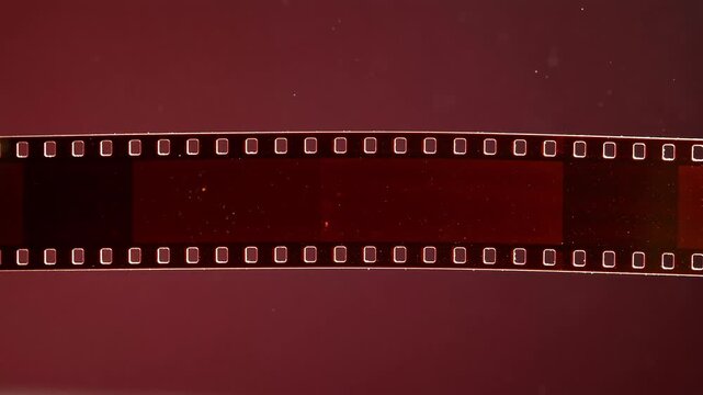 Horizontal vintage analogue 35mm photographic film strip with frame perforations on dark background
