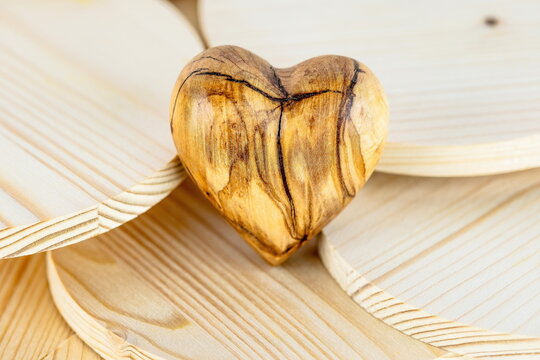 Cuore di legno d'ulivo lavorato a mano su sfondo di legno di abete con venature