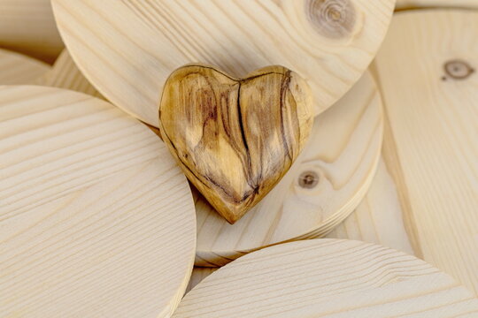 Cuore di legno d'ulivo lavorato a mano su sfondo di legno di abete con venature