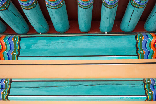 Traditional colorful dancheong patterns painted on wooden eaves and rafters of historic buddhist temple architecture in South Korea.