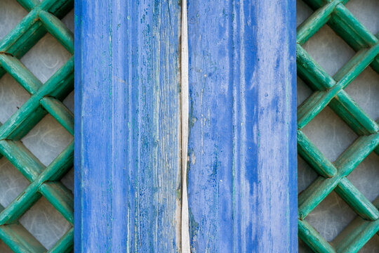 Close up detail of weathered blue wooden pillar and green lattice door pattern at traditional buddhist temple in South Korea.
