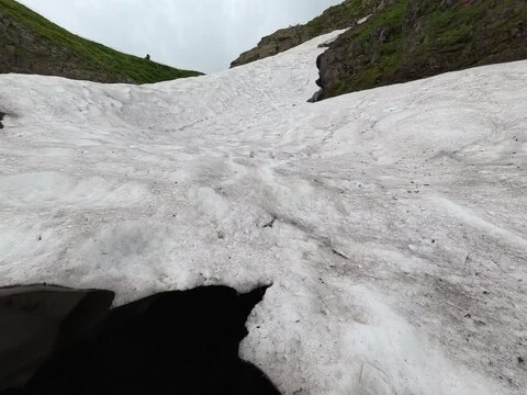 Melting snow patch and natural ice cave formed in the high alpine plateau of Savsat, Artvin, Turkey.