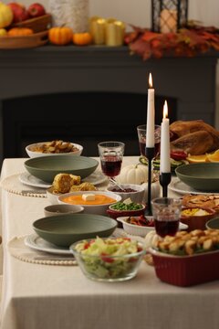 Happy Thanksgiving day. Festive dinner with delicious food, wine and burning candles on table indoors, closeup