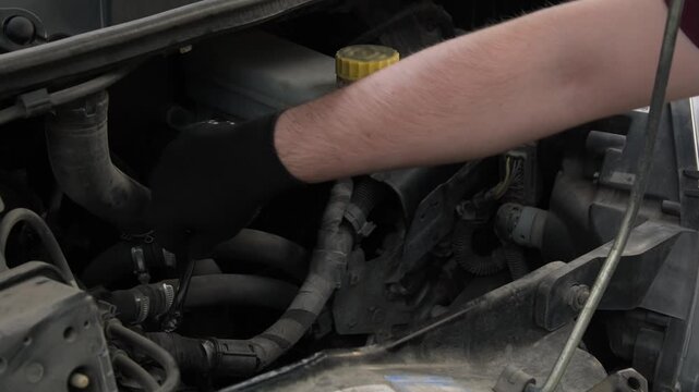 Close-up of a mechanic using a wrench to loosen a part under the hood of a car