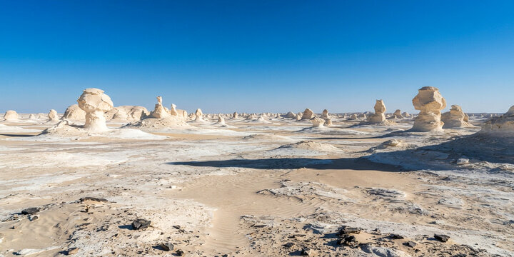 Unique white rock formations and mushroom-like desert landscape under a clear blue sky