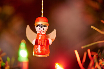 Fototapeta premium Angel, Christmas and tree with decoration closeup for December celebration or holiday season. Festive, flare and lights with Kitschmas ornament in apartment or home for cheer, joy or noel theme