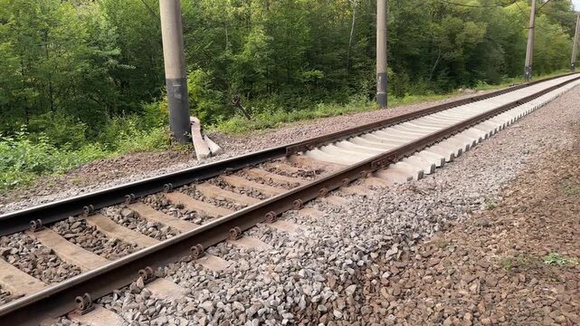 New railway rails and sleepers in Carpathians, close-up reveals rails bent and uneven, later aligned by track machines, rustic industrial detail of fragile infrastructure