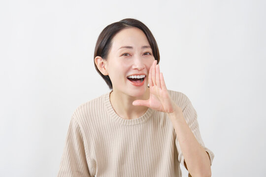 口元に手を添えて呼びかける女性　白背景
