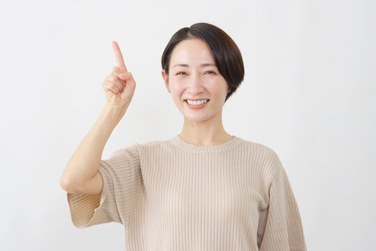 上を指差す笑顔の女性　ミドルエイジ　白背景