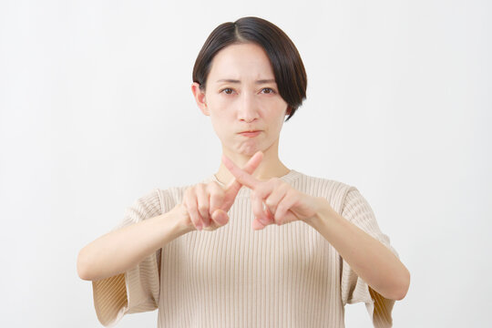 指でバツをつくる女性　ミドルエイジ　白背景