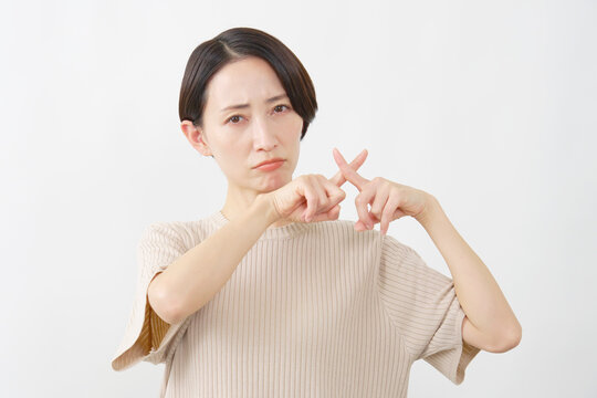 指でバツサインを示す女性　白背景