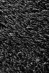 Full frame close up of black shaggy rug carpet texture background in monochrome tones. © sauloangelo