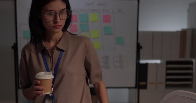 Woman software developer planning sprint on whiteboard flowchart with sticky notes in office