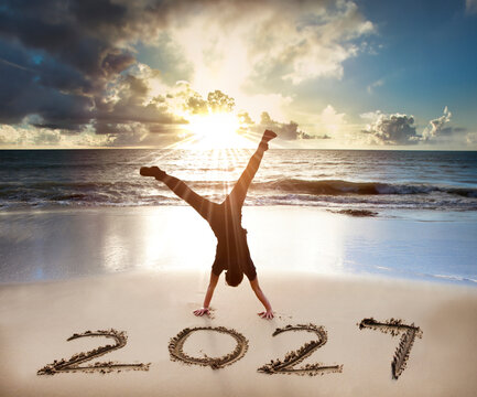  Young man handstand on the beach. happy new year 2027 concept