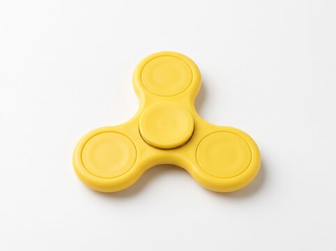 Yellow fidget spinner toy with three round bearing caps on white background, high angle view, stress relief hand toy
