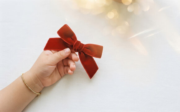 Child holding a dark red velvet hair bow for festive holiday styling and children fashion