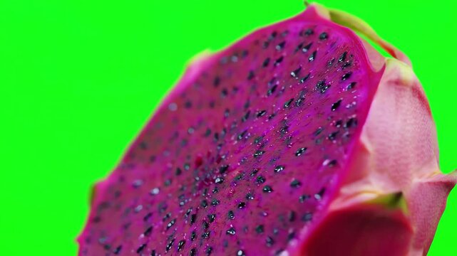 Detailed close up of a fresh dragon fruit slice rotating slowly against a bright green screen background for chroma key editing